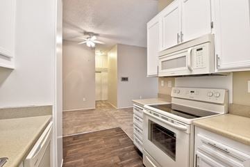San Diego apartment for rent - A kitchen with white cabinets and a stove top oven.