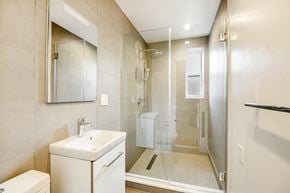 Brooklyn apartment for rent - A bathroom with a toilet, sink, mirror, and shower.