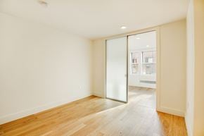 Brooklyn apartment for rent - A room with a wooden floor and a glass door leading to another room.