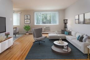 Philadelphia apartment for rent - Living room with wood flooring, beige walls, and air conditioning unit under windows. Opens to dining room.