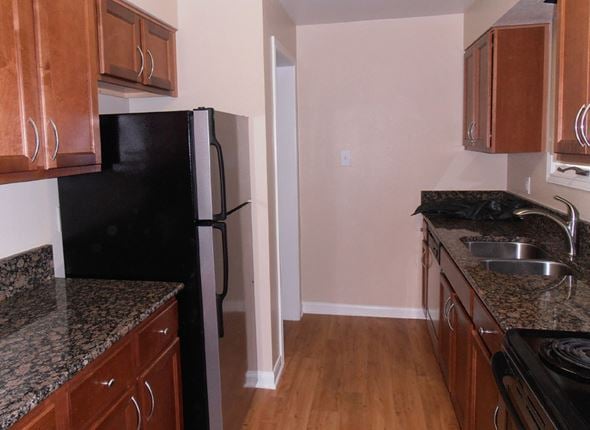 Austin apartment for rent - a kitchen with wood cabinets and a black refrigerator