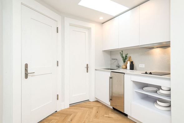 Boston apartment for rent - a small kitchen with white cabinets and a wood floor