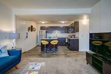 Kalamazoo apartment for rent - a living room and kitchen with a blue couch and yellow chairs