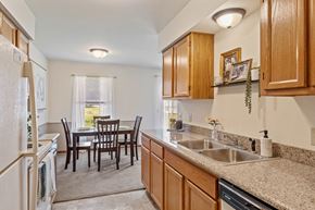 Grandville apartment for rent - A kitchen with wooden cabinets and a table set for four.