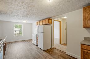 Caledonia apartment for rent - A kitchen with a white fridge and wooden cabinets.