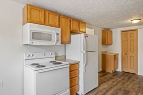 Caledonia apartment for rent - A white stove and microwave in a kitchen with wooden cabinets.