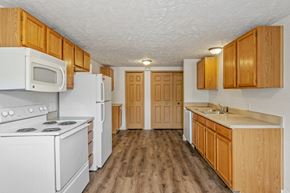 Caledonia apartment for rent - A kitchen with white appliances and wooden cabinets.