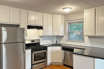 Oak Park apartment for rent - A kitchen with white cabinets and black countertops.