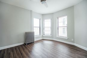 Chicago apartment for rent - an empty living room with a radiator and three windows