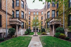 Chicago apartment for rent - exterior view of a brick apartment building with a sidewalk and green lawn