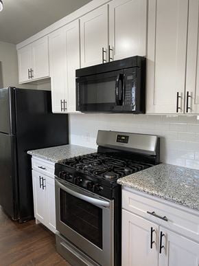 Denton house for rent - A black microwave is mounted on a white cabinet above a stove.