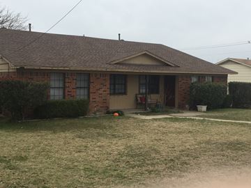 Denton triplex for rent - A house with a brown roof and a lawn in front.