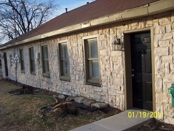 Denton triplex for rent - a stone house with windows and a black door