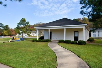 Tuscaloosa apartment for rent - A small white house with a black roof and a playground in the front yard.