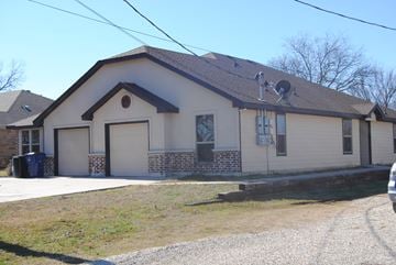 Aubrey triplex for rent - the front of a house with garage doors