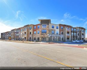 Denton apartment for rent - A multi-story building with a mix of brick and panel construction is under construction with a clear blue sky in the background.