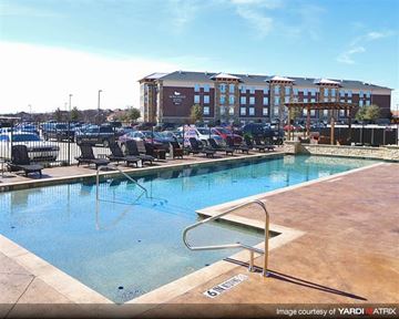 Denton apartment for rent - A pool with a slide in front of a building.