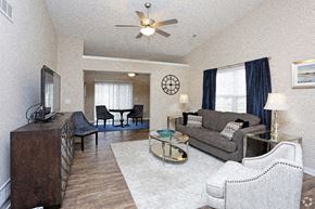 Ankeny apartment for rent - A living room with a grey couch, a black chair, a brown cabinet, and a ceiling fan.