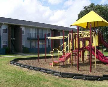 Harvey apartment for rent - a playground with a yellow umbrella and pink and yellow slides