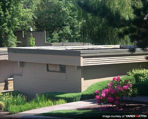 Portland apartment for rent - A house with a grey siding and a brown roof with a small window and a door.