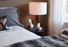 Harrison apartment for rent - a bedroom with a bed and a lamp and a table with candles and a plant