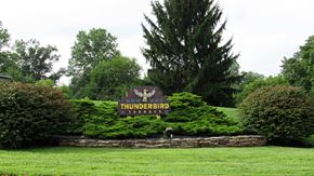 Dover apartment for rent - the sign for thunderbird estates sits in front of a green field and a tree