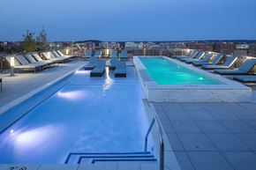 Washington apartment for rent - A swimming pool with lounge chairs and a lit poolside area.