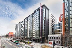 Washington apartment for rent - A street view of a city with modern buildings and a red sign on the left.