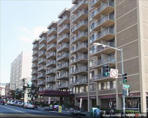 Washington apartment for rent - A tall apartment building with a red awning is on a street corner.
