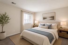 Middle River apartment for rent - A bedroom with a large bed, a potted plant, and a framed picture on the wall.