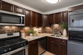 Middle River apartment for rent - A kitchen with dark brown cabinets and a black stove top oven.