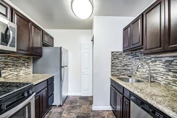 Laurel apartment for rent - A kitchen with dark brown cabinets and a granite countertop.