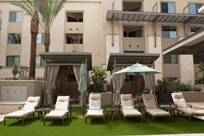 Scottsdale apartment for rent - an outdoor lounge area with chairs and umbrellas in front of an apartment building
