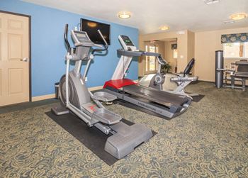 A gym with exercise equipment in a hotel room