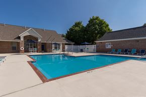 Akron apartment for rent - A large outdoor swimming pool with a red brick building in the background.