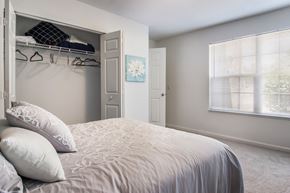 Akron apartment for rent - A bedroom with a large bed and a closet with clothes hanging.
