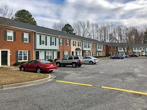 Greenville townhouse for rent - A red car is parked in a parking lot in front of a row of townhouses.