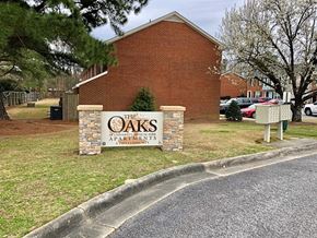 Greenville townhouse for rent - A brick building with a sign that says "Oaks" in front of it.