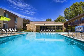 Davis apartment for rent - A swimming pool with chairs around it and a building in the background.