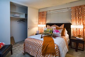 Davis apartment for rent - A bedroom with a bed covered in an orange and white patterned comforter and a small table beside it.