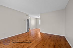 Long Beach apartment for rent - A room with wooden floors and a logo for Beach Front Property Management.