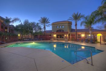 A pool surrounded by palm trees and a building in the background