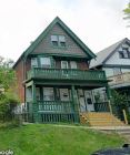 Milwaukee triplex for rent - A green house with a porch and a balcony.