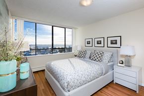 New Westminster apartment for rent - A bedroom with a large bed and a view of the city.