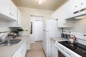 New Westminster apartment for rent - A white kitchen with a stove, sink, and refrigerator.