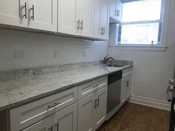 Evanston apartment for rent - a kitchen with white cabinets and a sink and a window