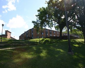Mankato apartment for rent - a large brick building on a grassy hill with trees