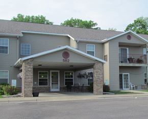 Red Wing apartment for rent - the front of a large apartment building with a porch and a table and chairs outside