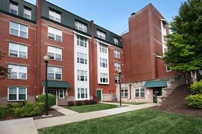 Pittsburgh triplex for rent - an exterior view of a brick building with green grass and a sidewalk