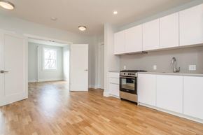 Somerville apartment for rent - an empty kitchen with white cabinets and a wood floor